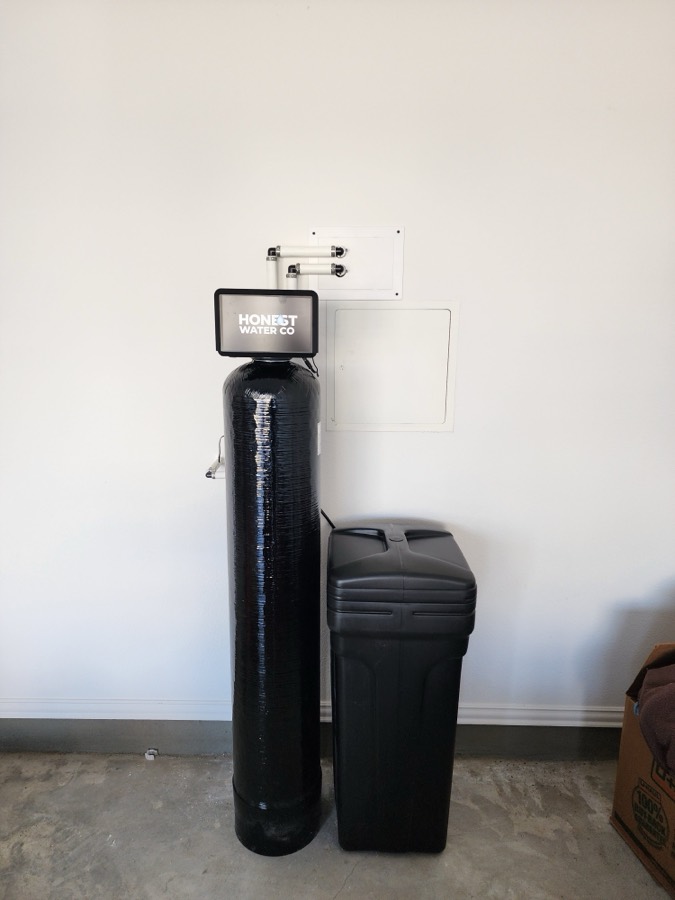 Twin-tank whole-home water treatment system installed in a garage
